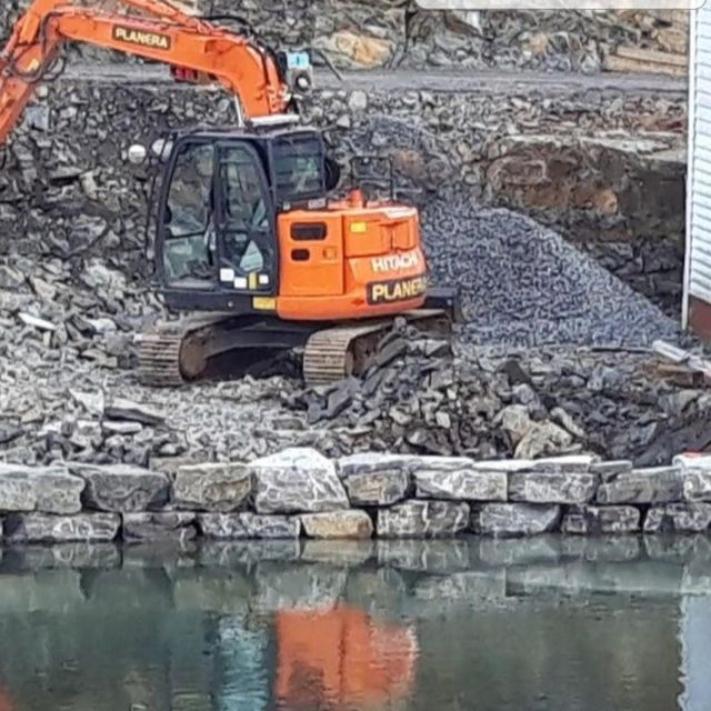 Gravemaskin i arbeid ved sjø